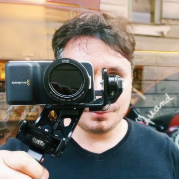 Matteo Curcio holding a Blackmagic Pocket Cinema Camera on a handheld gimbal in front of a shopfront