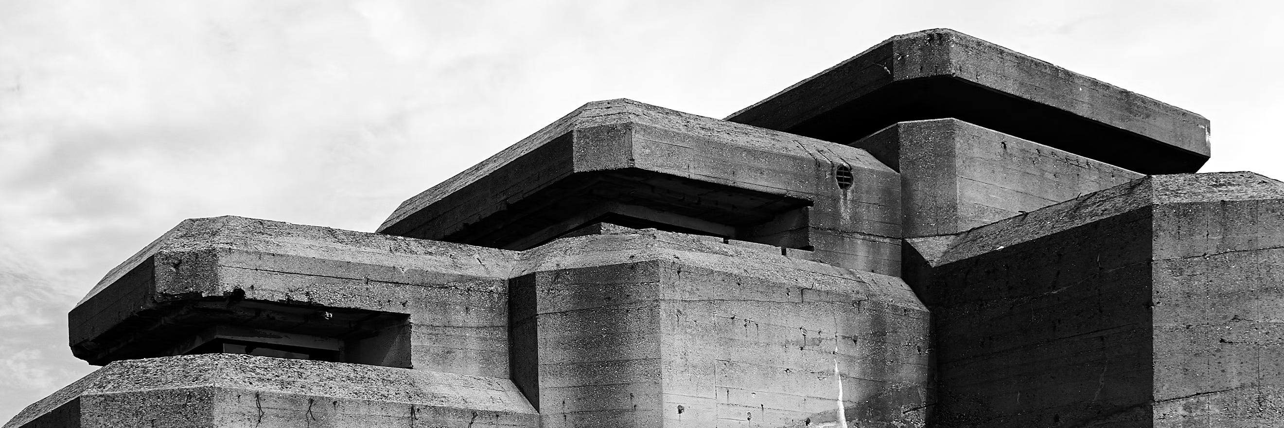 Black and white photo of a monumental concrete bunker structure under a cloudy sky.