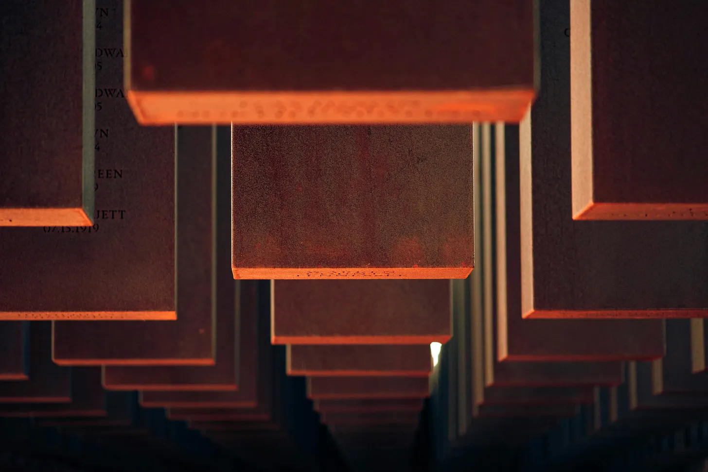 Rows of suspended rectangular panels lit in warm orange tones against a dark background.